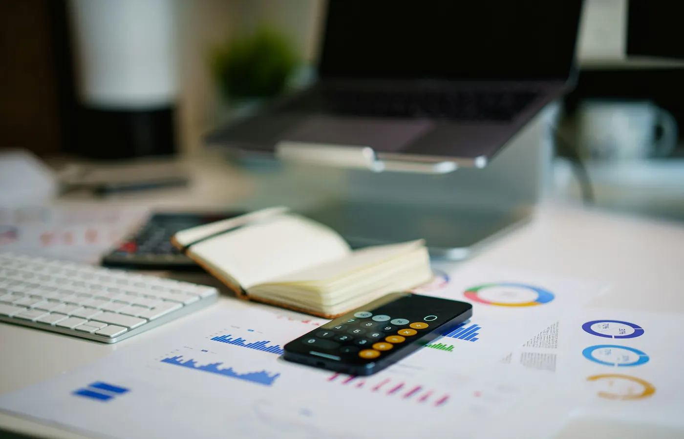Monthly bookkeeping workspace with financial reports, calculator, notebook, and laptop.