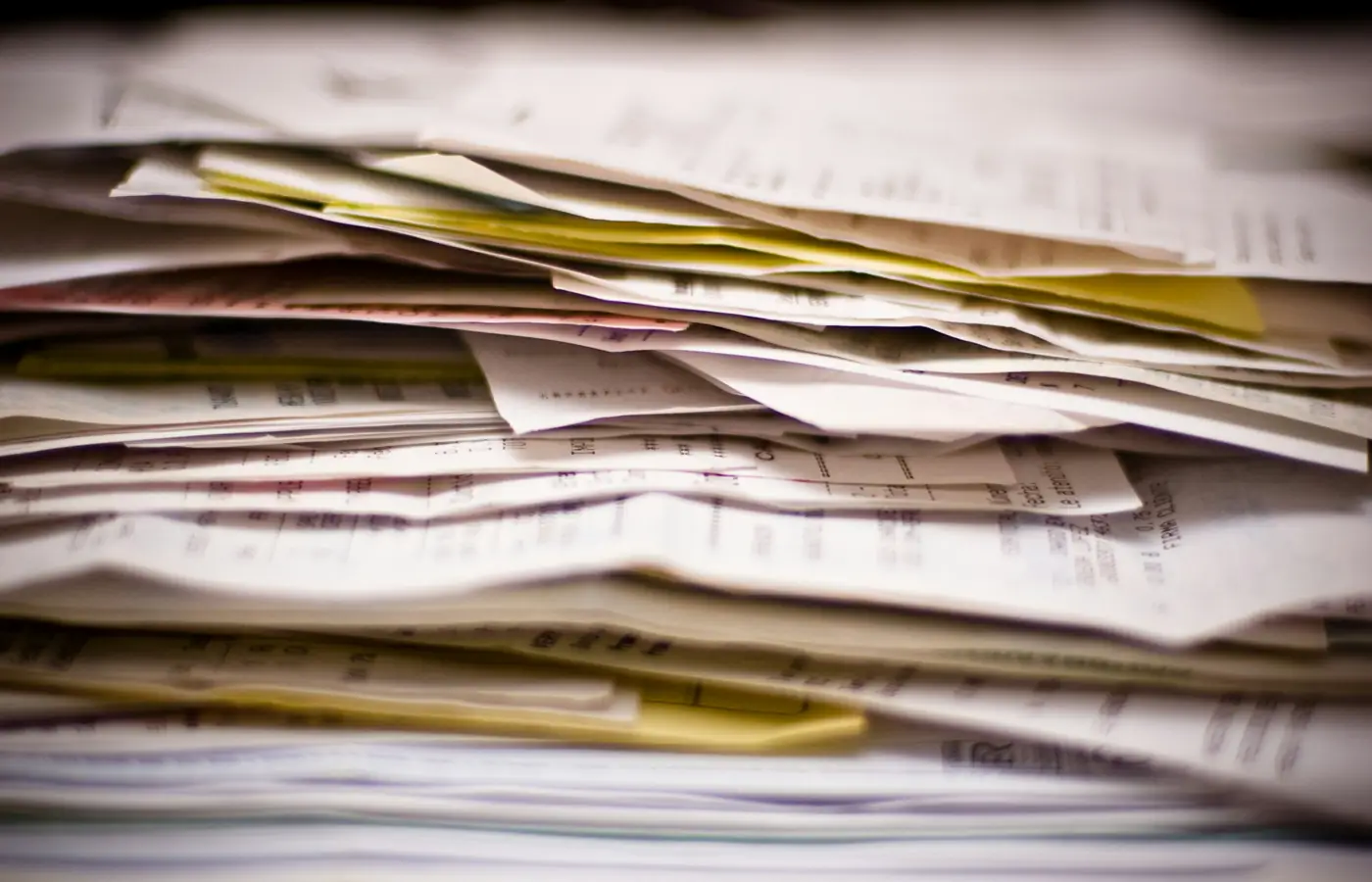 Stack of disorganized business receipts and paperwork for QuickBooks cleanup.